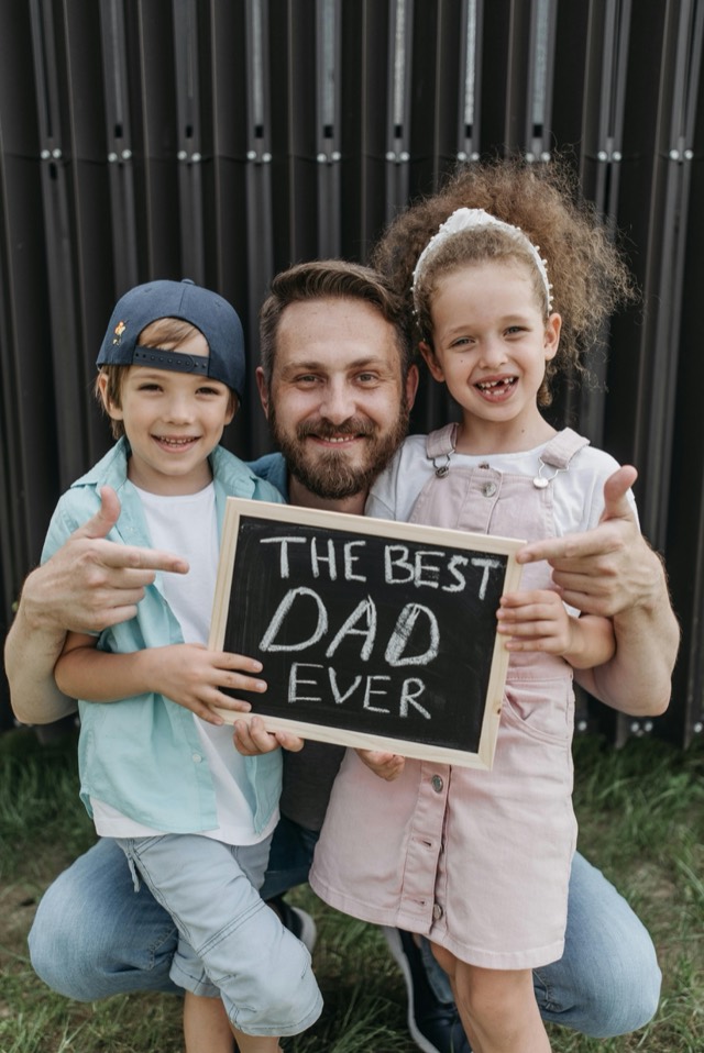 A dad with his son and daughter holding a 'Best Dad Ever' sign
